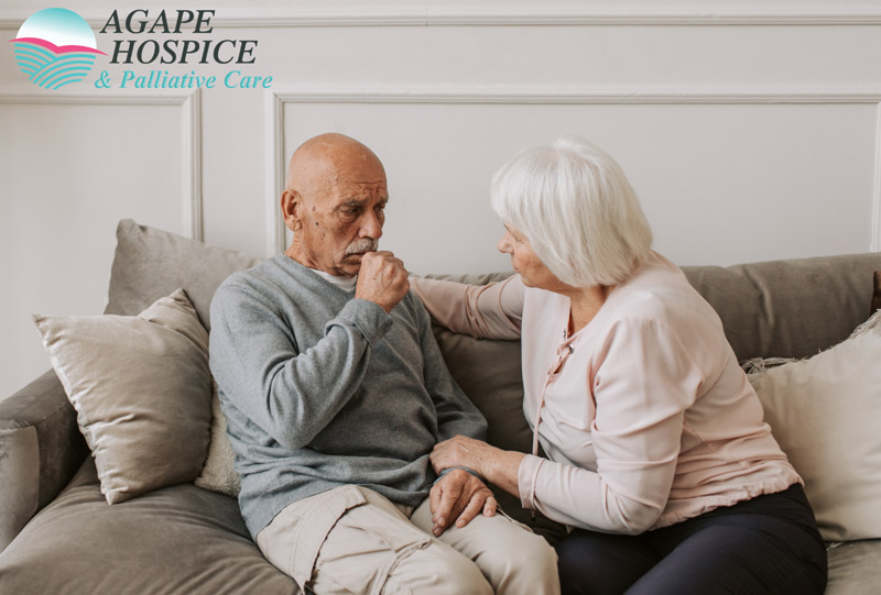 A male hospice patient coughs into his hand while his caretaker comforts him in LA or Orange County