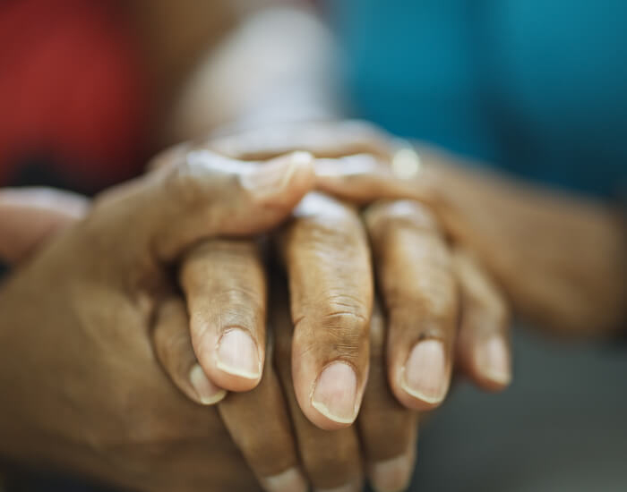 A black hospice patient and a black nurse hold hands in Torrance, CA.