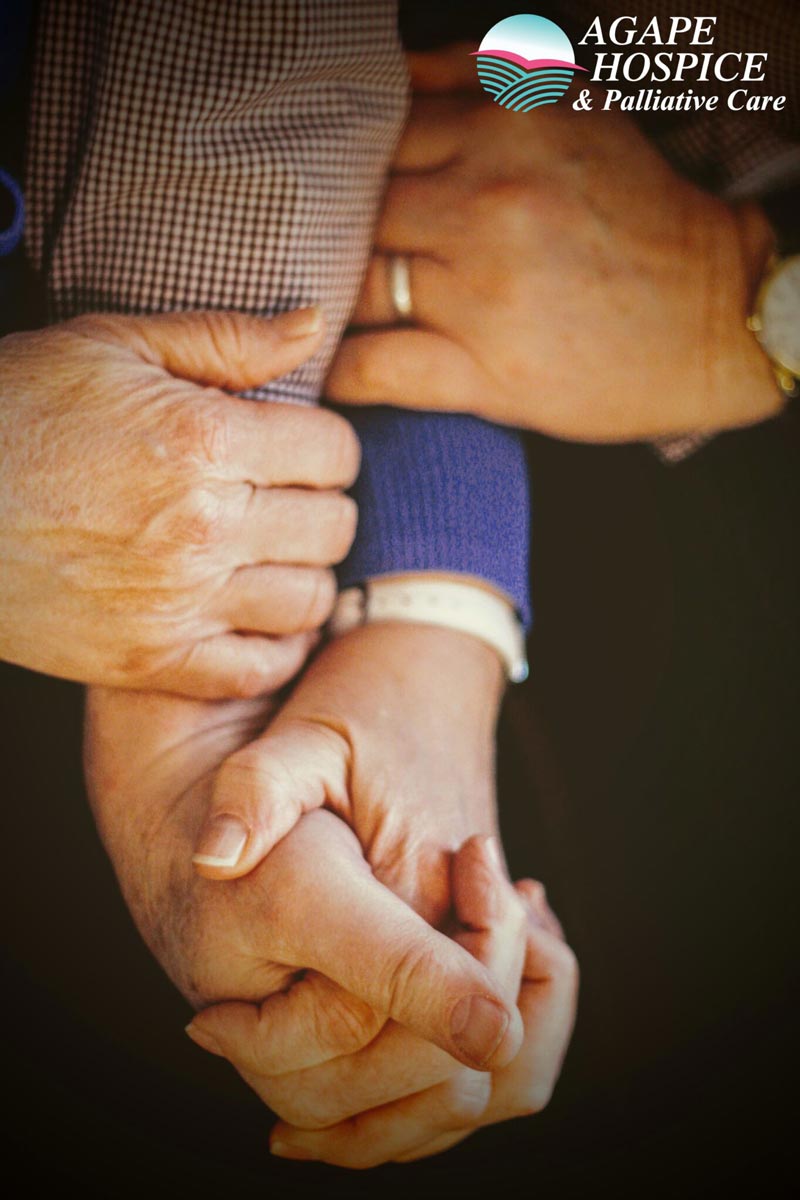 A family holds hands with someone in hospice in Torrance, CA.
