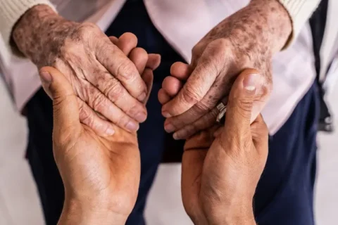 Caregiver holding hands with a senior woman patient