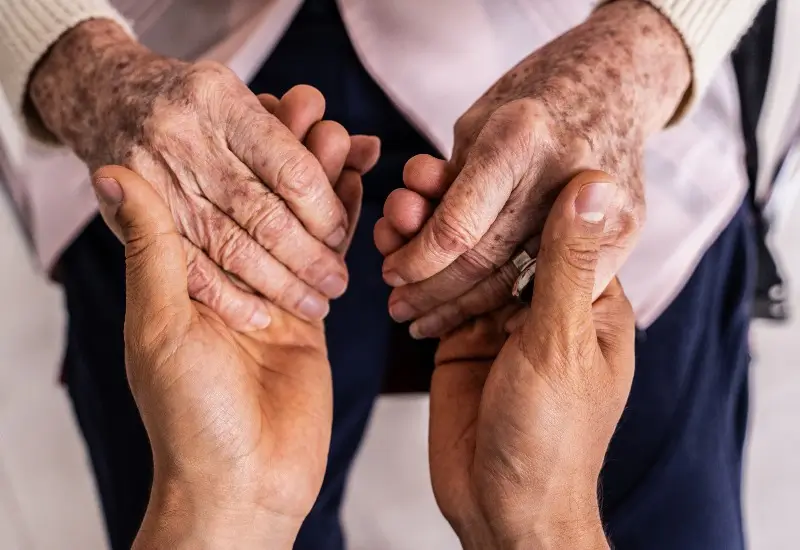 Caregiver holding hands with a senior woman patient