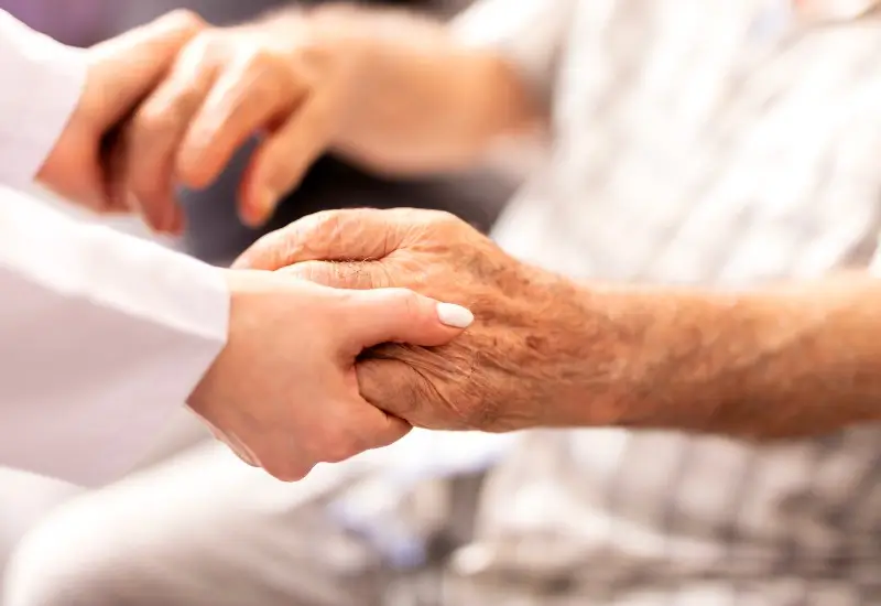 Nurse holding her senior patient's hand giving support