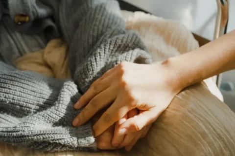 Woman comforting patient by holding their hands