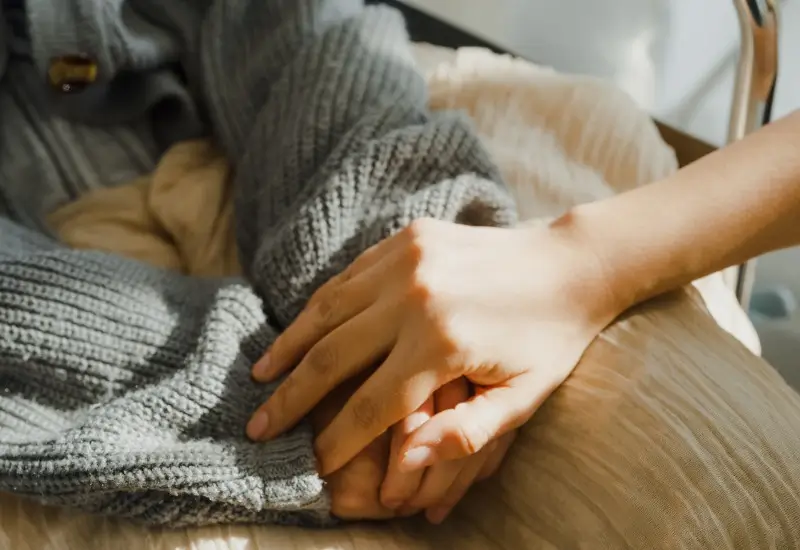 Woman comforting patient by holding their hands