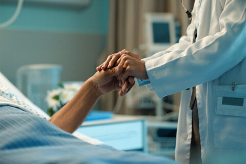 A hospital physician holds the hand of a DNI patient