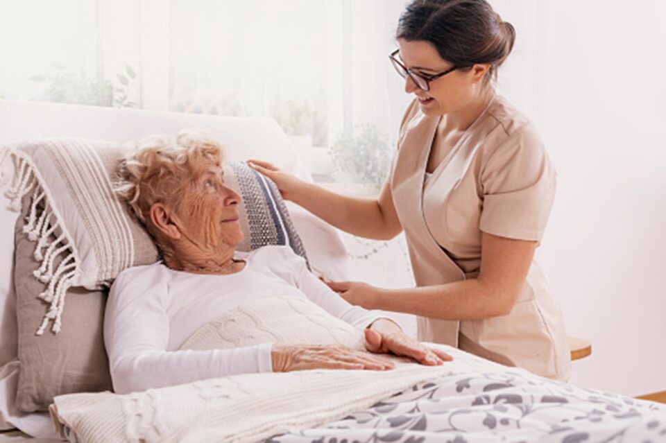 An in-home hospice nurse tends to a senior woman in bed