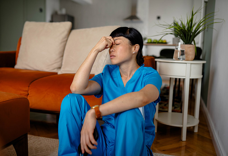 A caregiver sits on the floor feeling stressed and burnt out
