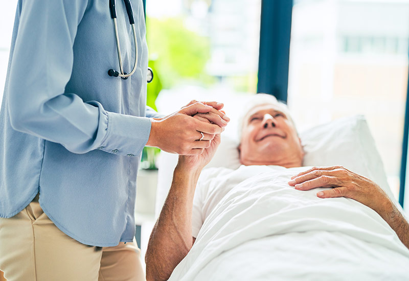 A hospice physician comforts a senior man lying in bed