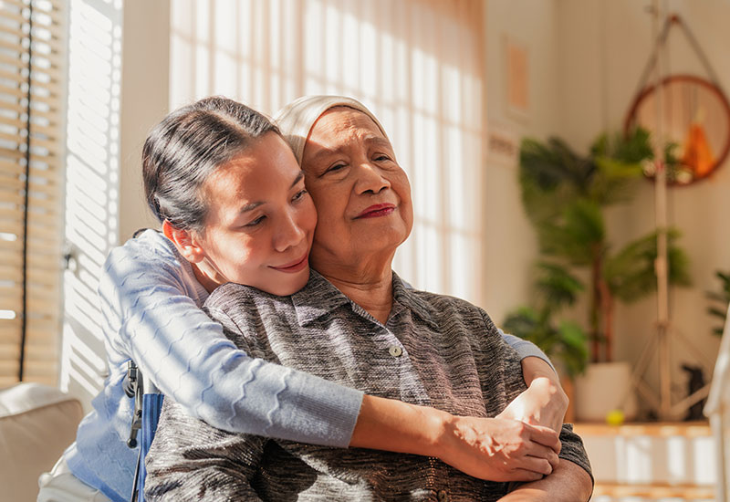 A lady hugs her mother, who is nearing the end of her life