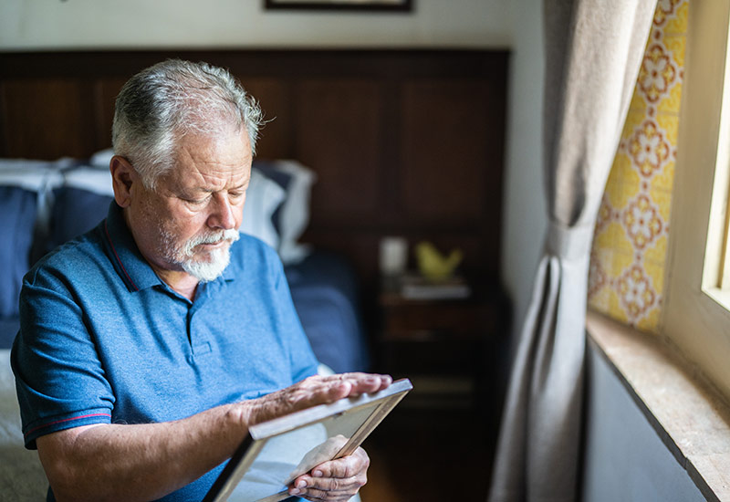 A man looks at a photo while grieving the loss of his spouse