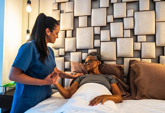 Care provider helping a patient rest comfortably in bed in LA and Orange Counties