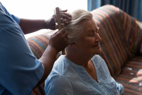 Hospice care provider gently brushing the hair of a lady at home in Los Angeles & Orange Counties