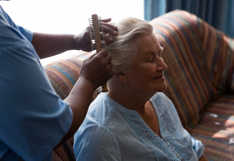 Hospice care provider gently brushing the hair of a lady at home in Los Angeles & Orange Counties